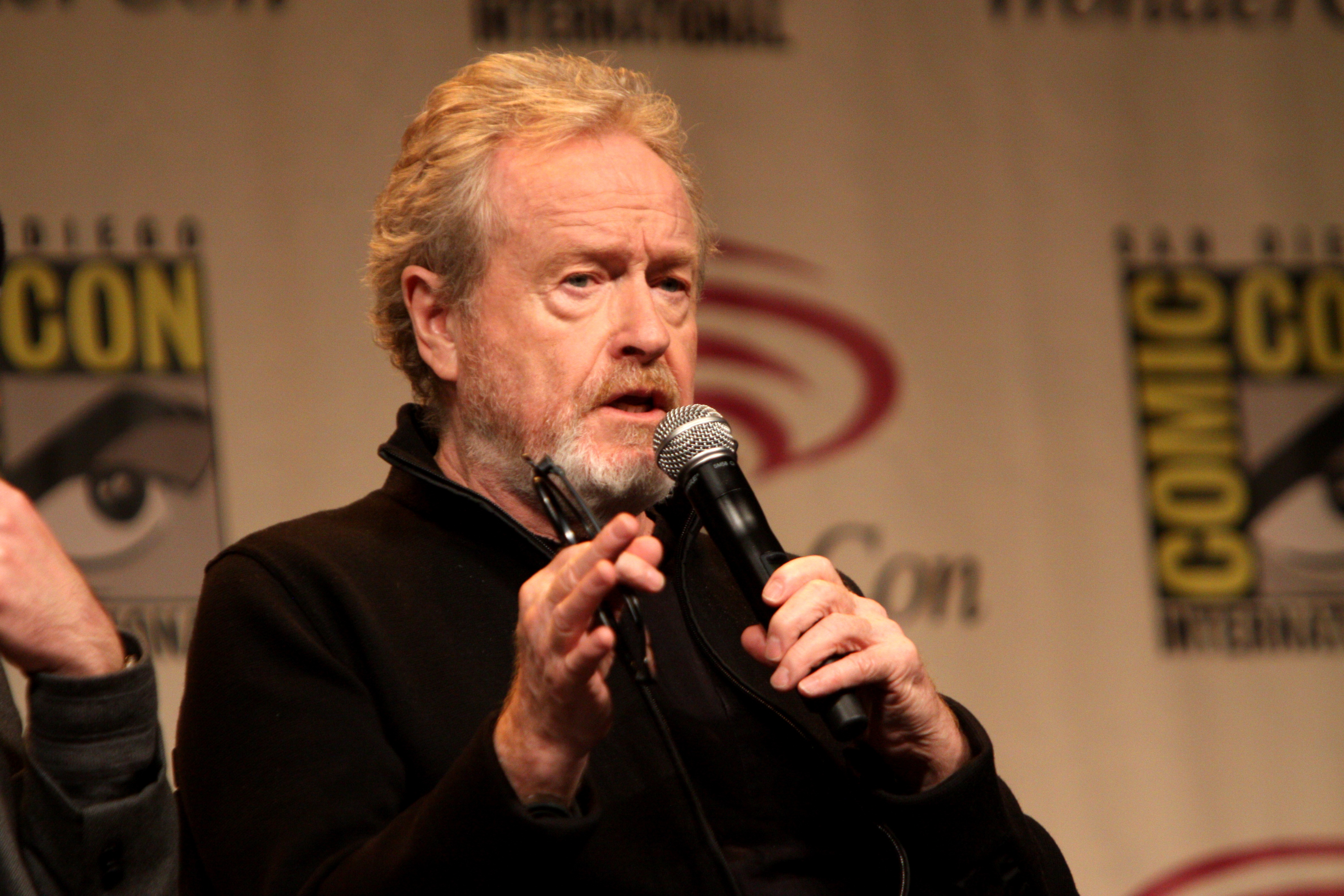 Ridley Scott en una alfombra roja junto al logo de Alien de fondo